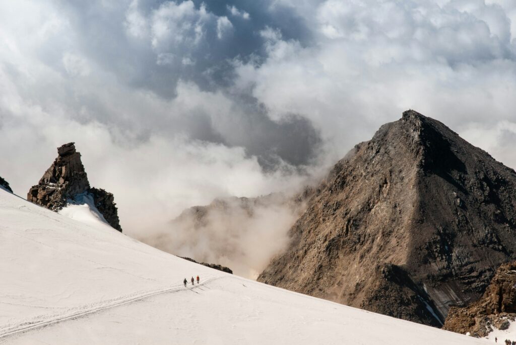 Climbers walking on Gran Paradiso mountain ridge in clouds and mist Italy