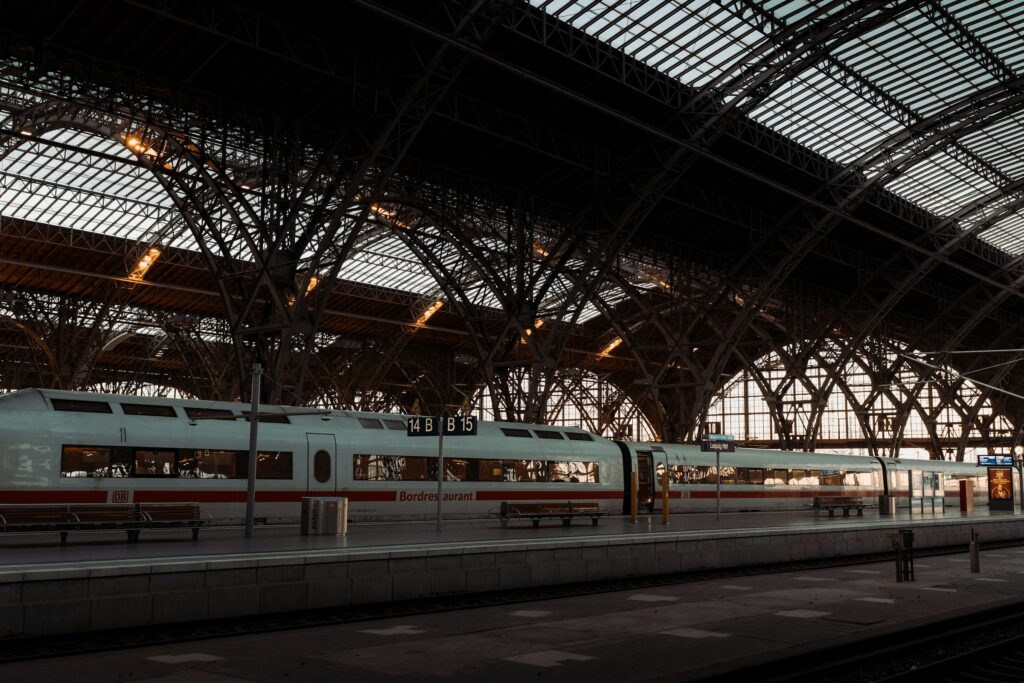 European intercity train at grand railway station with ornate iron arched roof at dusk