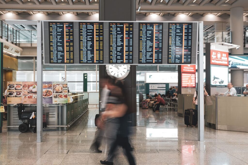Travelers in motion blur at airport terminal with departure flight screens