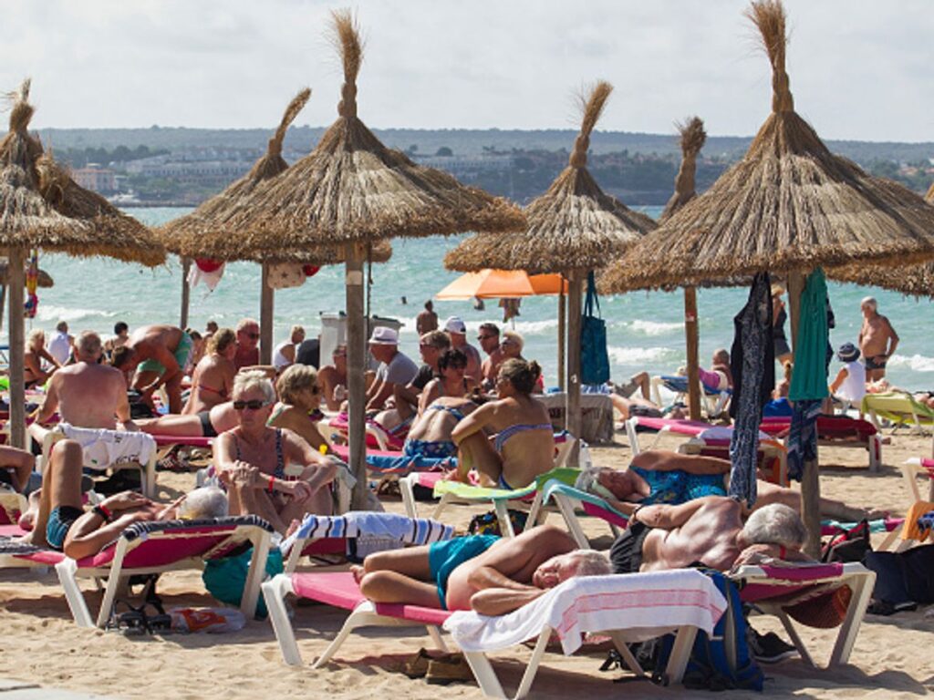 Sunbed Wars Escalate: Tenerife Towel-Tossing Goes Viral as German Court Sides With Holidaymakers | Empty sun loungers reserved with towels beside a resort pool with palm trees