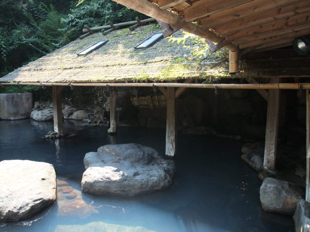 Outdoor rotenburo hot spring bath surrounded by rock and trees at Kurokawa Onsen, Kyushu