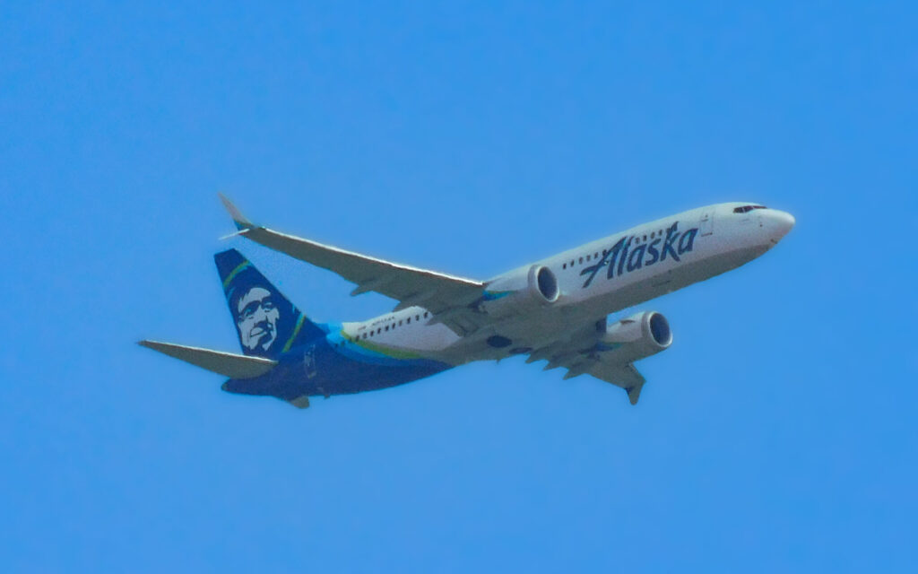Alaska Airlines Boeing 737 MAX 8 climbing after takeoff against a clear blue sky
