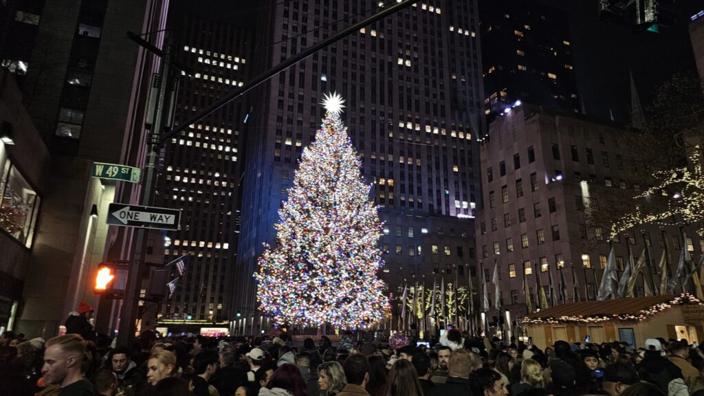 Crowds beneath the lit Rockefeller Center Christmas tree in Midtown Manhattan