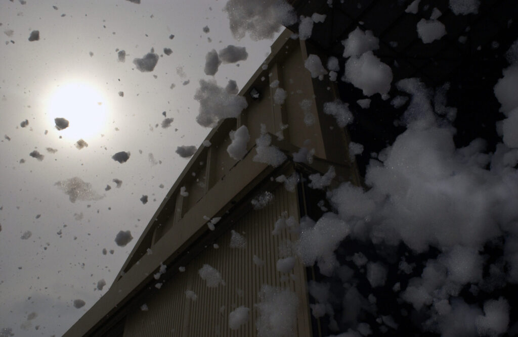 High-expansion foam spilling out of an aircraft hangar door during a system test