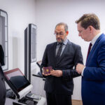 Officials inspecting a passport beside EES self-service kiosks at St Pancras International