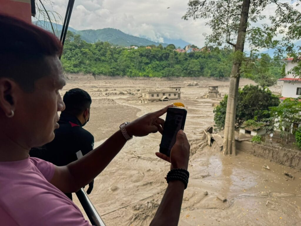 Flash Floods Kill at Least 98 in Nepal and China as Hundreds of Tourists Remain Missing | People photograph the swollen debris-choked Trishuli River after Nepal flash floods