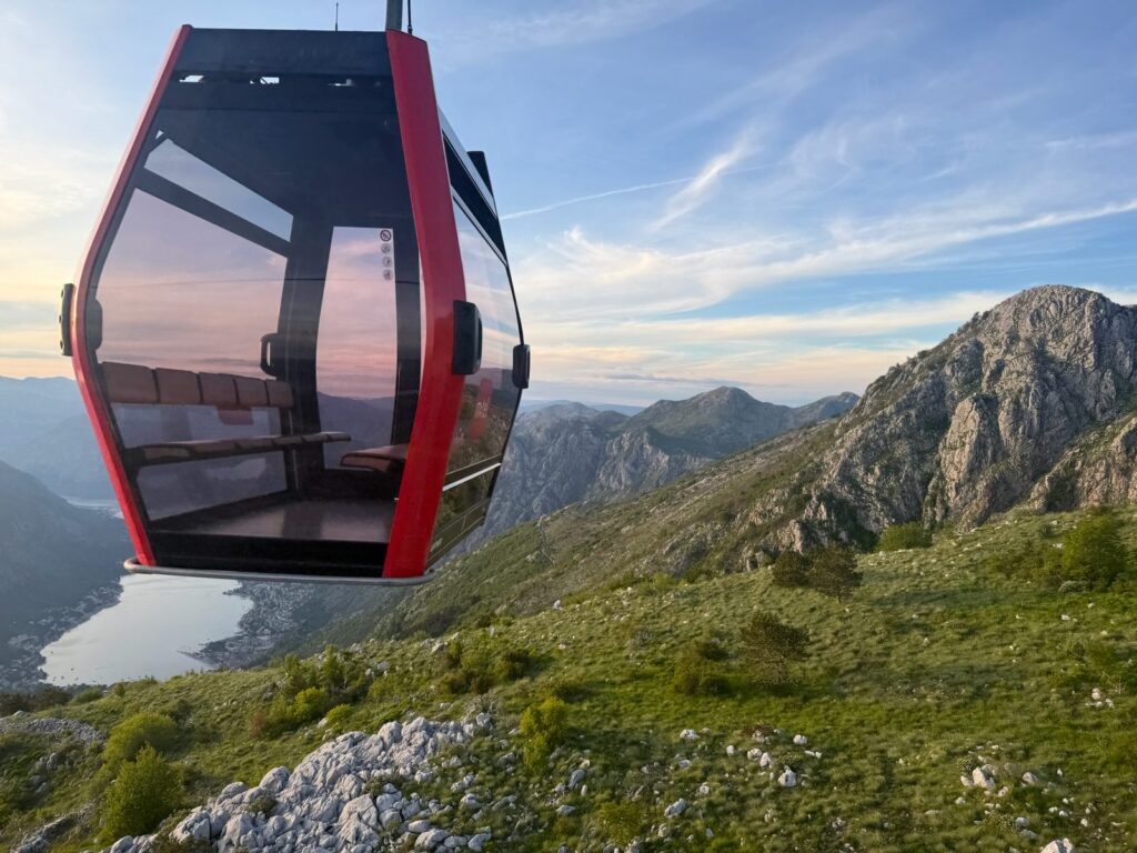 Red Kotor Cable Car cabin flying against the mountain ridge above the Bay of Kotor