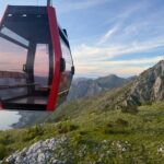 Red Kotor Cable Car cabin flying against the mountain ridge above the Bay of Kotor