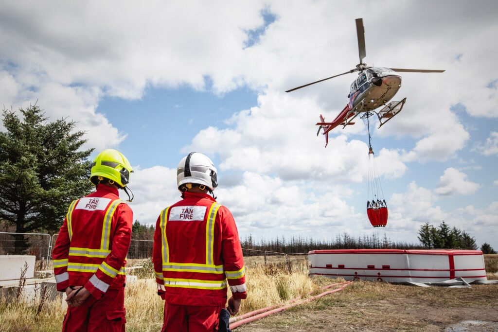 Welsh firefighters watch a helicopter water drop during the UK wildfire emergency alert