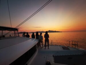 Sail With Us(DE-AT-CH) skippered yacht sailing across the Mediterranean at sunset
